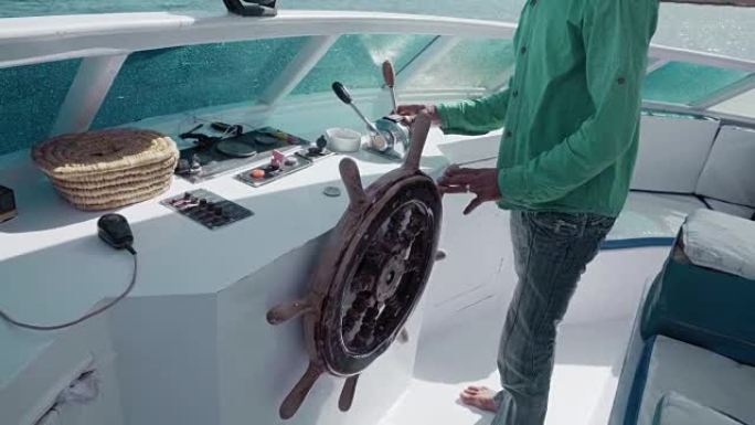无法识别的主人在复古方向盘和控制杆的帮助下管理游艇。商业或生活管理、度假或旅游的概念