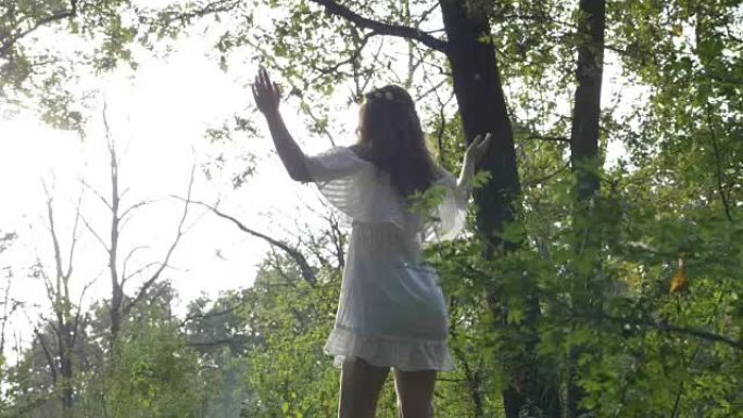 天使般的白衣女人向阳光瑜伽致敬，在大自然中放松