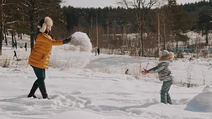 妈妈和小女儿在慢动作中玩雪。冬季快乐休息