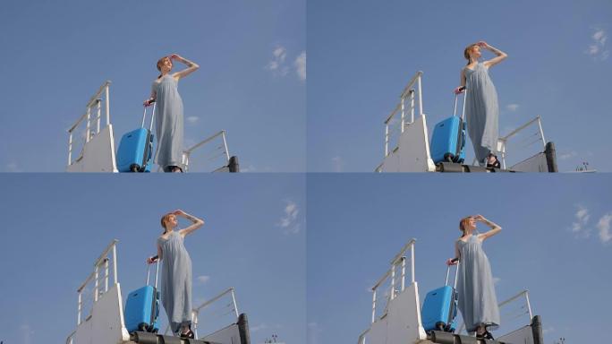 带着旅行包的年轻女子站在背景蓝天上的可移动楼梯上