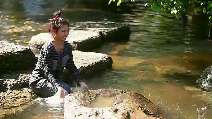 年轻的女孩坐在小溪旁sc起，独自玩水