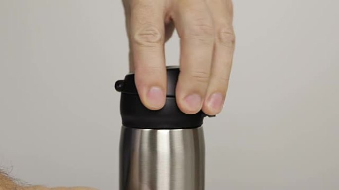 男人的手在灰色背景上打开热水瓶