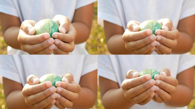 儿童手握复活节彩蛋在阳光背景下的特写镜头