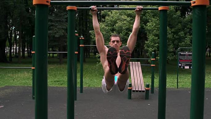 运动肌肉发达的人在公园的双杠上进行腹部锻炼。男子抬腿。男人在酒吧做角度。