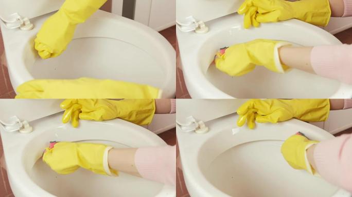 妇女的双手特写黄色橡胶手套用海绵洗马桶。侧视图。