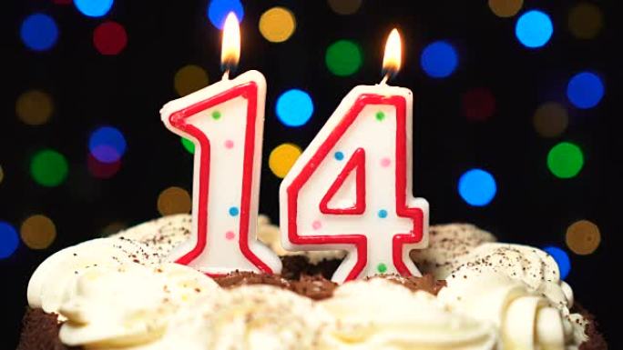 蛋糕上的第14号-十四岁生日蜡烛燃烧-最后吹灭。彩色模糊背景
