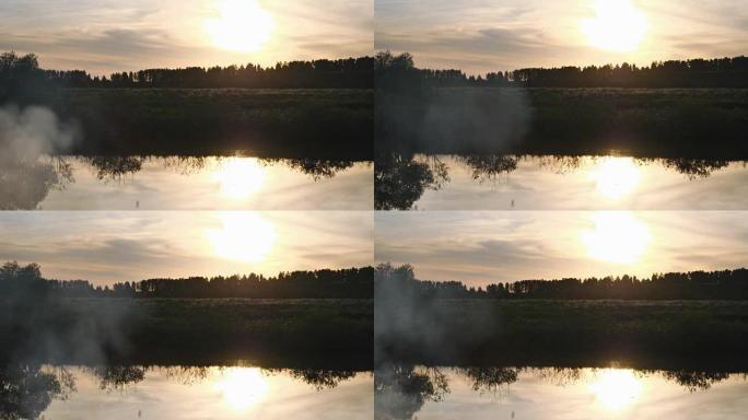 日落-天空中的日落及其在河流水表面的反射。夏夜。前景中的烟杆