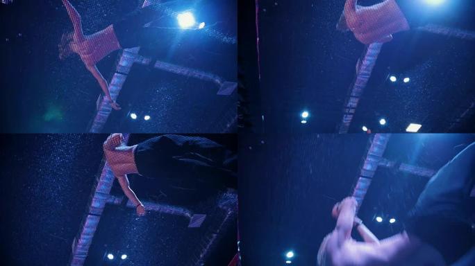 年轻人赤裸上身的杂技演员在蹦床上跳跃 -- 慢动作，底部视图