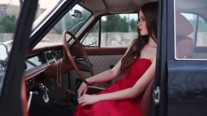 年轻女子穿着红色连衣裙坐在一卷汽车运输工具后面放松