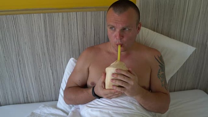 一个男人在床上喝椰奶