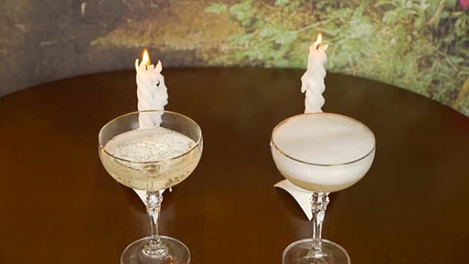 浪漫的夜晚。一个男人的手用葡萄酒盛装香槟。蜡烛在燃烧。安静舒适的夜晚。期待假期。