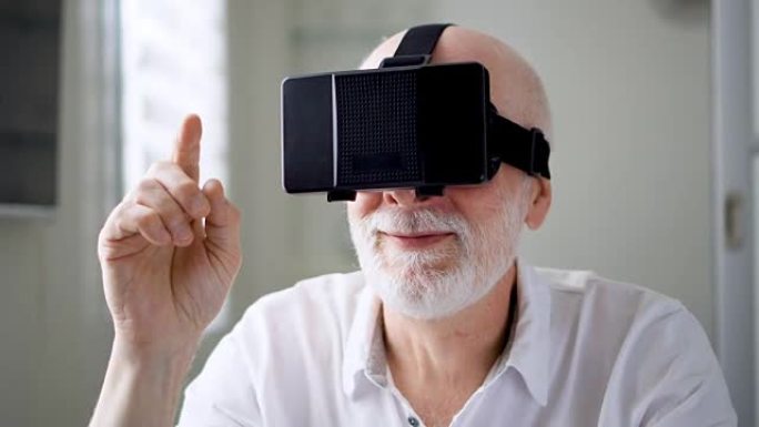 英俊的高级男子在白色使用VR 360眼镜在家里。进行浏览、缩放和点击手势