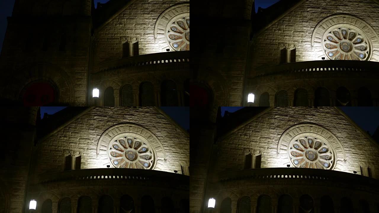 夜晚的哥特式教堂，带有美丽的圆形染色玻璃窗