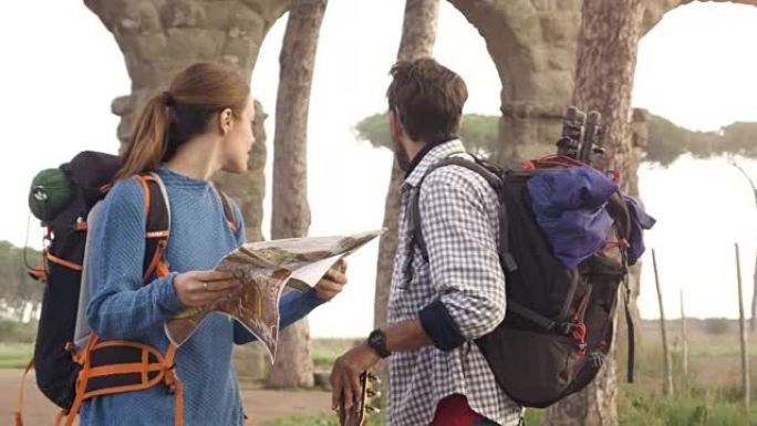 快乐的年轻夫妇背包客游客阅读地图指南，在罗马公园的罗马渡槽拱门附近迷失方向