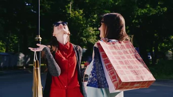 两个女人热情地谈论她们的购买。手里拿着购物袋