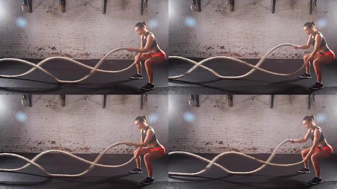 运动的年轻女子在室内用绳子做体操。慢动作