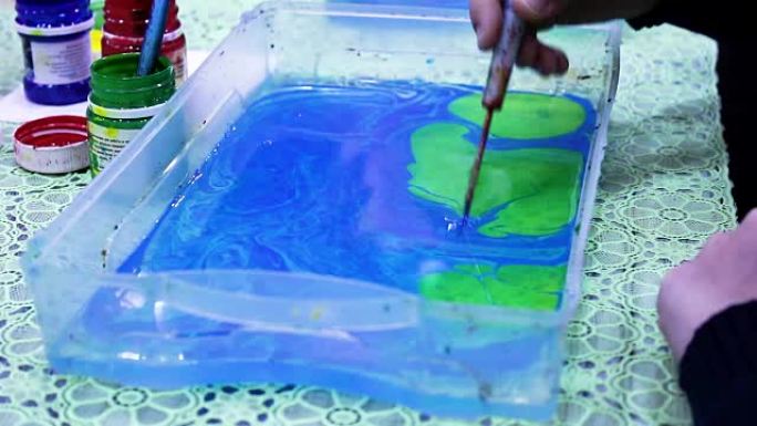 绿色墨水油漆溅到蓝色的水面上。油漆滴在水面上。孩子学画水漆