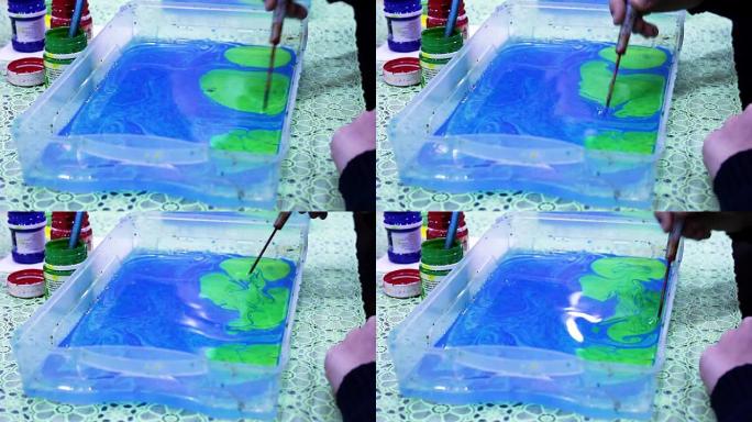 绿色墨水油漆溅到蓝色的水面上。油漆滴在水面上。孩子学画水漆