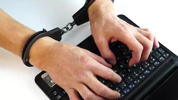 男性手铐在笔记本电脑上打字，犯罪预防，黑客攻击，信息技术，数字犯罪处罚，数据安全，保存软件