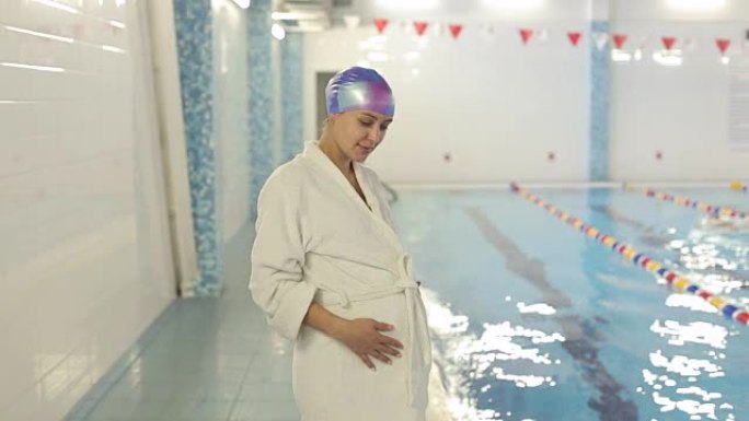 身披白袍的怀孕少女在泳池旁。