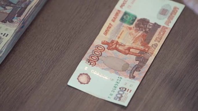 女性手触摸桌子上的5,000卢布钞票