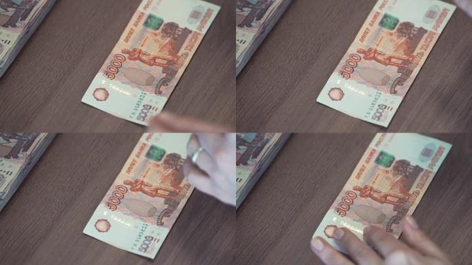 女性手触摸桌子上的5,000卢布钞票