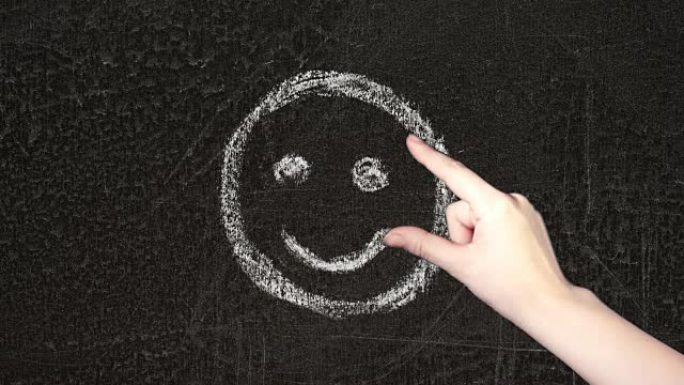 在黑板上手绘不快乐的笑脸。女性的手翻阅并选择微笑。
