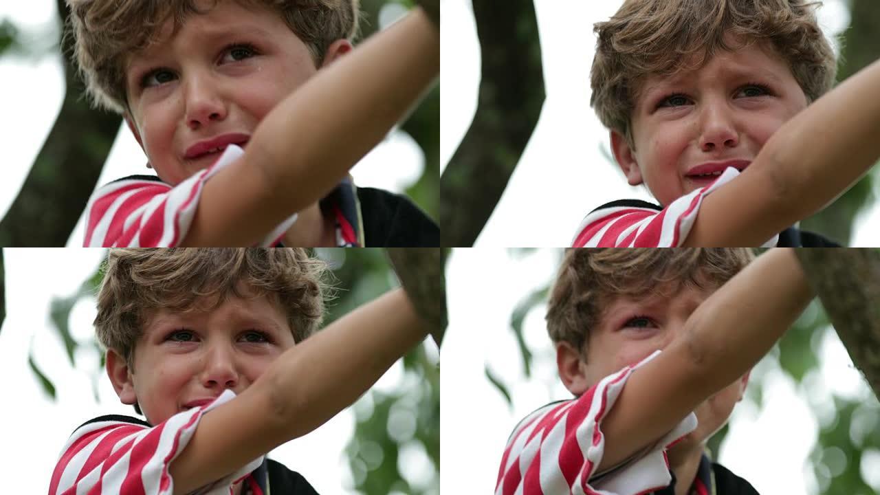 哭泣的孩子。现实生活中真实的坦率地抽泣着一个泪流满面的孩子在树顶上。痛苦的哭泣小男孩在4k中哭泣
