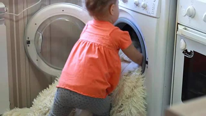 有趣可爱的小女孩把脏东西放在洗衣机里。婴儿和洗衣房