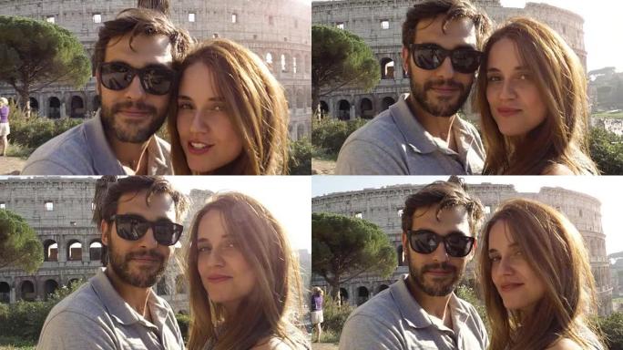 快乐的年轻夫妇游客在日落时在罗马斗兽场前拍摄自拍视频，微笑着享受摄像机的视点