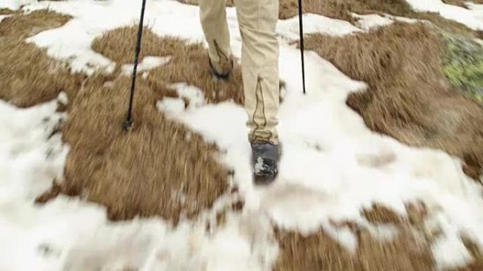 背包男徒步行走在雪道上。后面的腿细节。真正的背包客成人徒步旅行或徒步旅行在秋冬野外野外的山区自然，大