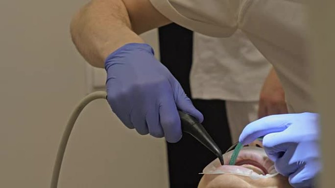 牙医正在现代牙科诊所治疗病人。正畸医生与助手一起工作。在操作中，使用了围堰。客户正在做假牙。医生和助