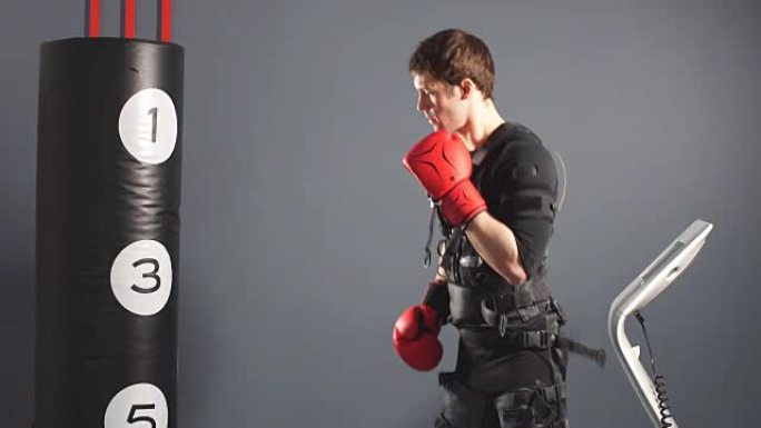 训练期间让男人戴上拳击手套。健身房电刺激套装拳击手