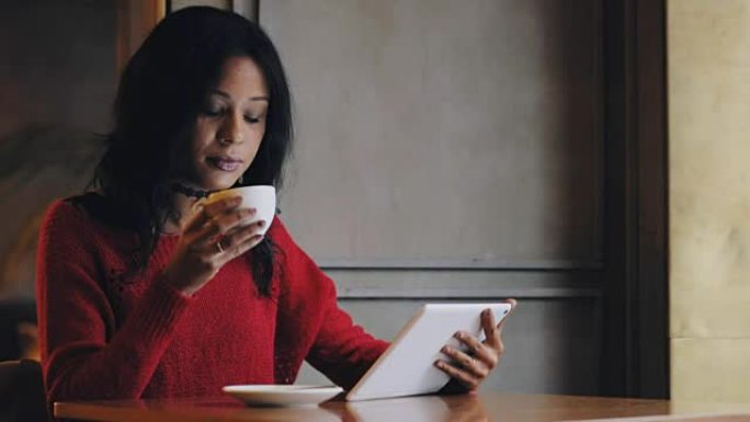 女人使用平板电脑在咖啡馆喝咖啡