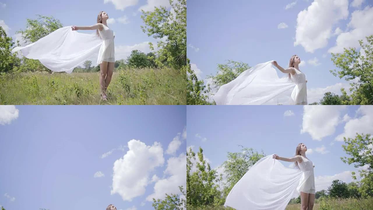 年轻漂亮的女人拿着白布在风中。全长镜头