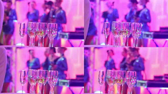 女子音乐团体剪影背景上的香槟眼镜，女子音乐乐队在餐厅或酒店大堂表演