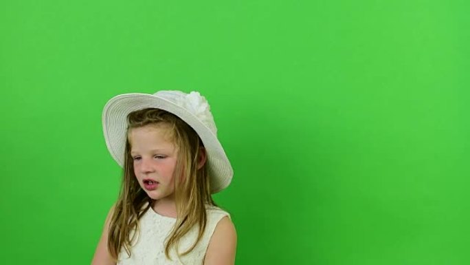 可爱的小女孩在色度关键背景上唱歌。小女孩穿着浪漫的衣服。白帽子和婚纱。色度关键背景。