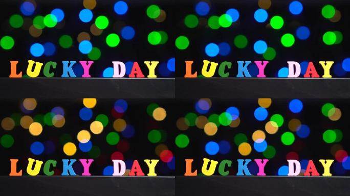 五彩缤纷的词汇 “幸运日” 来自抽象模糊灯光前的多色木制字母bokeh背景
