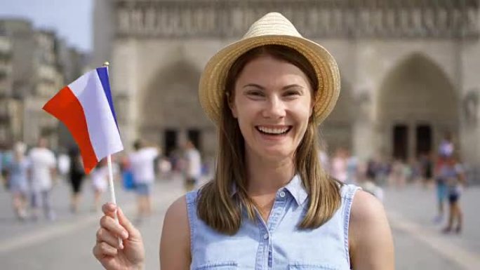 快乐的女孩享受假期。戴着帽子的游客站在巴黎圣母院附近。挥舞法国国旗