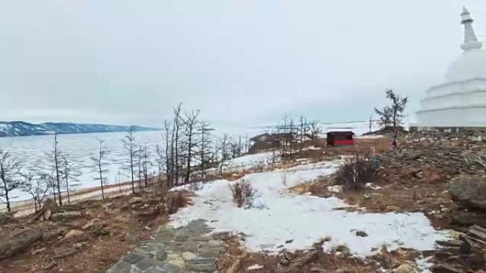 女人在贝加尔湖冰上的旅行。视点视图。关闭独特的佛教佛塔布尔汉纪念碑象征神秘的历史仪式岛Ogoi景观山