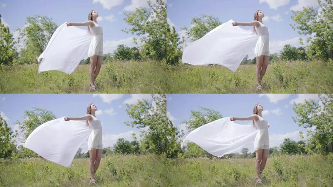 年轻漂亮的女人拿着白布在风中。全长拍摄。慢动作