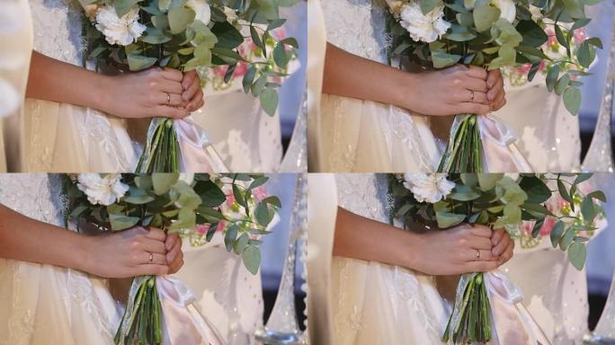 穿着白色婚纱的年轻新娘手中的美丽新娘花束。关闭大束新鲜的白玫瑰和郁金香花在女性手中。手持鲜花的匿名新
