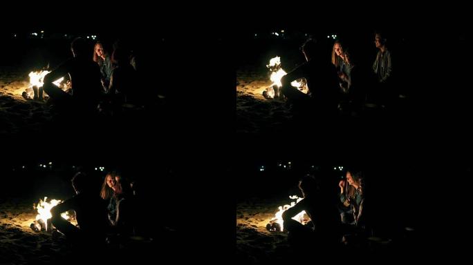 深夜坐在火炉旁的年轻人的背景图。开朗的朋友一起聊天，一起玩乐，喝啤酒