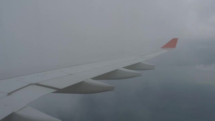 透过飞机窗户看到的云和天空。在云层上方飞行的飞机机翼。人们从飞机的窗户看天空，使用空运来旅行。多云天