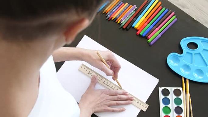 女孩用铅笔和尺子在纸上画线，顶视图
