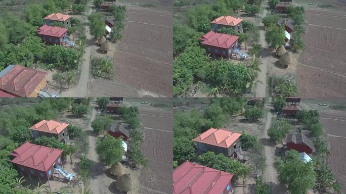 空中垂直射击俯瞰着木制高跷房屋穿过村庄的土路