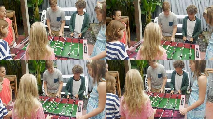 年轻女孩对年轻男孩玩桌上足球，女孩得分获胜
