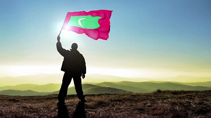 成功剪影男子胜利者挥舞马尔代夫国旗山顶上，Cinemagraph循环背景