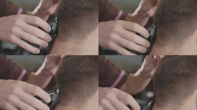 男理发师用电动剃须刀理发。