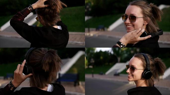 一个年轻女孩在街上或公园户外散步的跟踪镜头。开朗快乐。在她的短发上扎马尾辫，戴着墨镜，戴上耳机